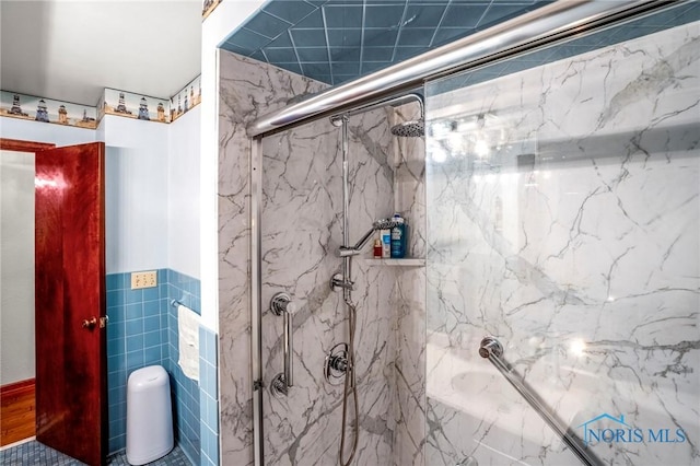 bathroom featuring tile walls, a tub with marble appearance, and a marble finish shower