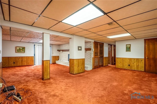 finished basement with carpet, wooden walls, a paneled ceiling, and wainscoting