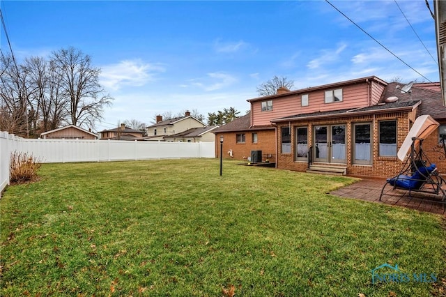 rear view of property with central air condition unit, a fenced backyard, a yard, brick siding, and a patio area