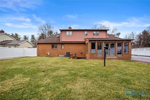 rear view of house with a yard, a fenced backyard, and brick siding