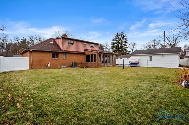 back of property featuring brick siding, a lawn, and fence