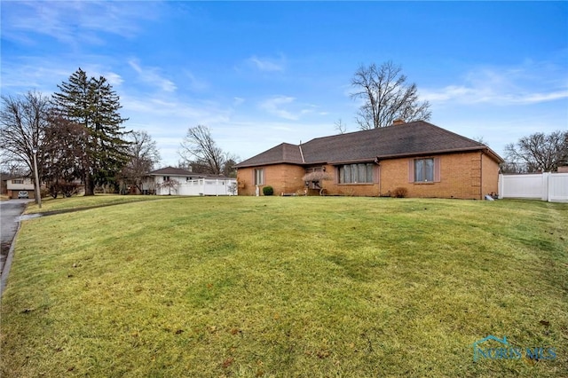 view of front of property with a front yard, fence, brick siding, and a chimney