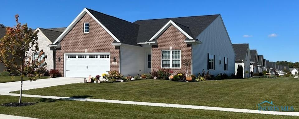 view of front of property featuring a garage, brick siding, concrete driveway, and a front yard