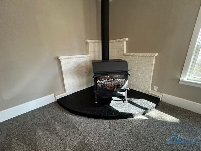 interior details featuring carpet flooring, baseboards, and a wood stove