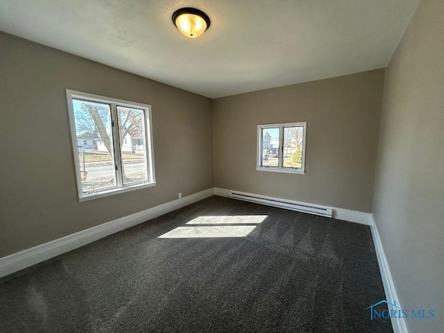 spare room with dark carpet, baseboards, a healthy amount of sunlight, and a baseboard radiator