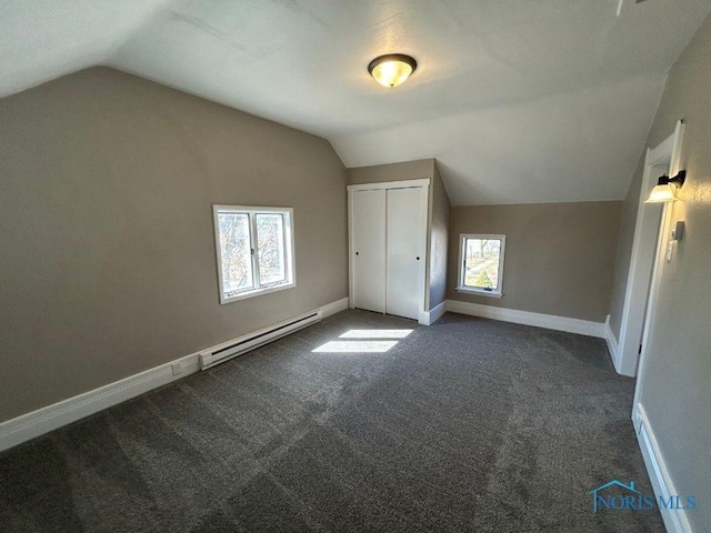 bonus room with a baseboard heating unit, vaulted ceiling, baseboards, and dark carpet