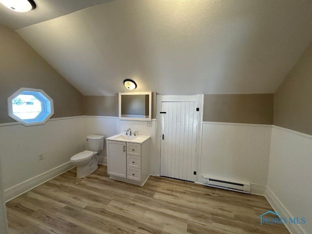 bathroom with toilet, wood finished floors, a wainscoted wall, and baseboard heating