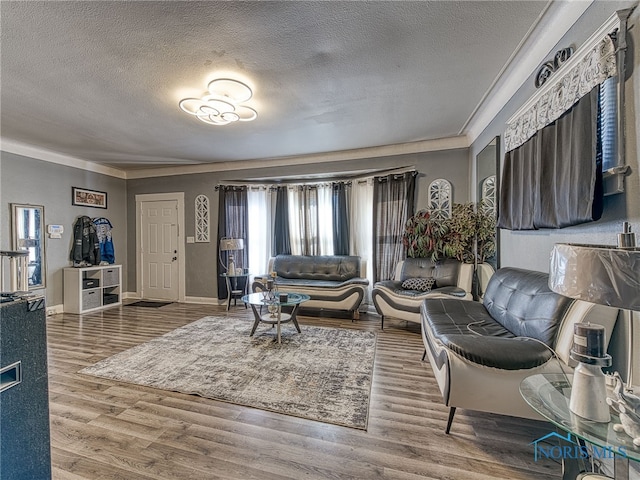 living area with ornamental molding, a textured ceiling, baseboards, and wood finished floors