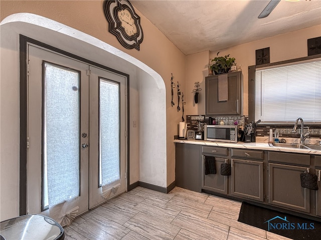 kitchen with a sink, stainless steel microwave, arched walkways, and french doors