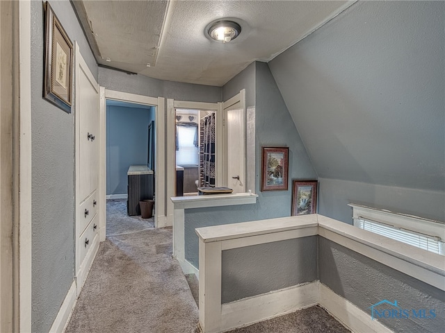 bathroom with baseboards, a textured ceiling, vaulted ceiling, and a textured wall