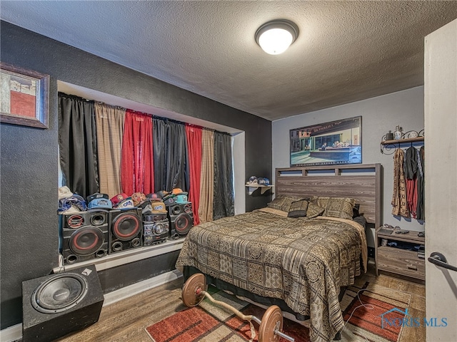 bedroom featuring wood finished floors, a textured wall, and a textured ceiling