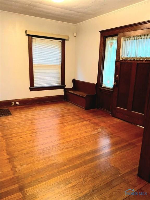 foyer with visible vents, wood finished floors, and crown molding