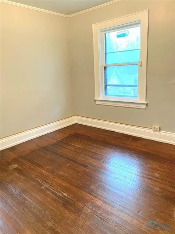 spare room featuring baseboards, wood-type flooring, and crown molding