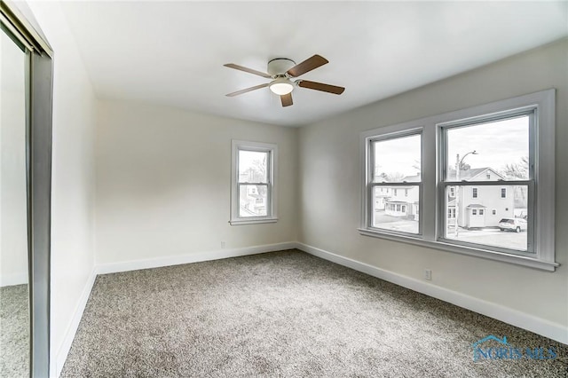 carpeted spare room featuring ceiling fan and baseboards