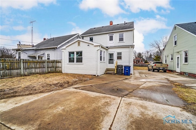 rear view of house featuring entry steps and fence