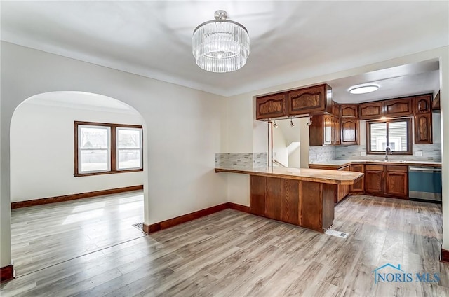 kitchen featuring visible vents, light countertops, dishwashing machine, a peninsula, and a sink