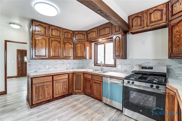 kitchen with backsplash, stainless steel range with gas cooktop, dishwasher, light countertops, and a sink