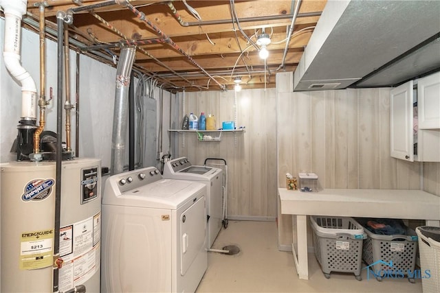 laundry area featuring washer and clothes dryer, laundry area, gas water heater, and wood walls