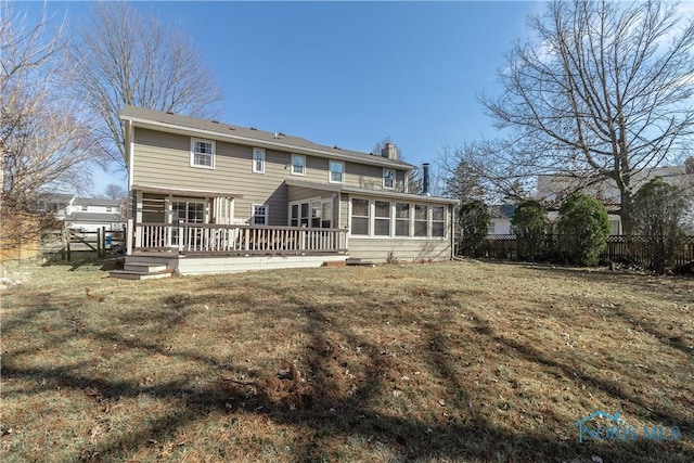 rear view of property with fence, a chimney, a yard, a sunroom, and a deck