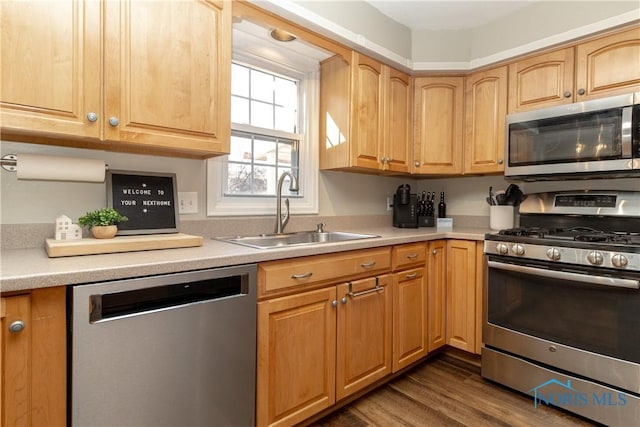 kitchen with a sink, stainless steel appliances, dark wood finished floors, and light countertops