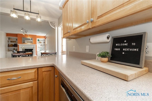 kitchen featuring dishwasher, light countertops, built in features, and a fireplace