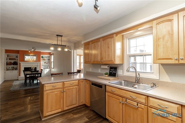 kitchen with a sink, a peninsula, dishwasher, dark wood-style flooring, and a healthy amount of sunlight