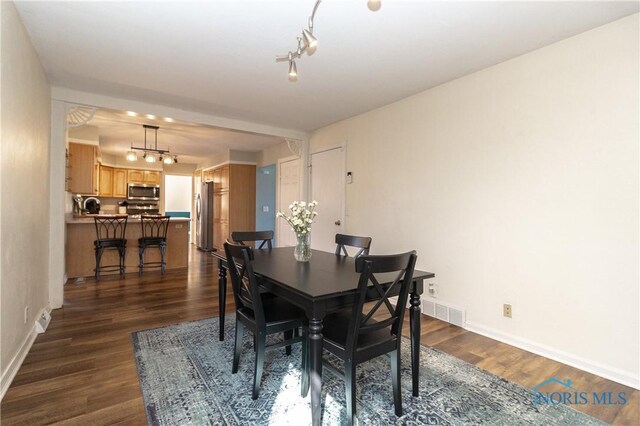 dining area with dark wood-style floors, visible vents, and baseboards