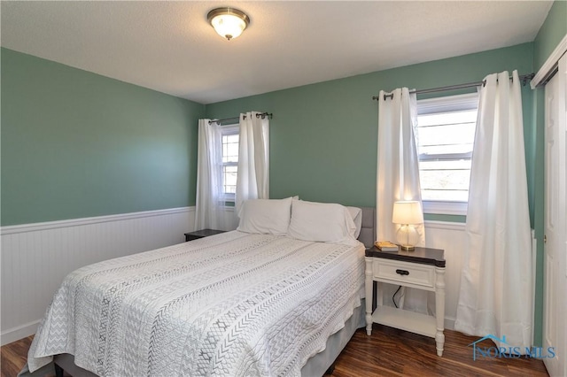 bedroom with dark wood-style floors and wainscoting