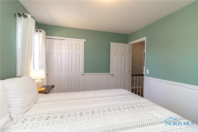 bedroom featuring a closet and a wainscoted wall