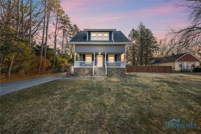 view of front facade with a porch, a yard, fence, and driveway