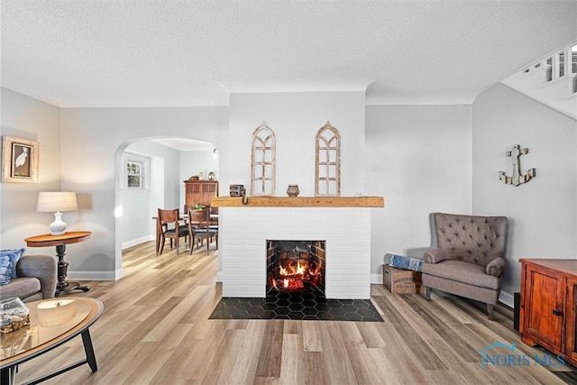 living area with baseboards, wood finished floors, arched walkways, and a textured ceiling