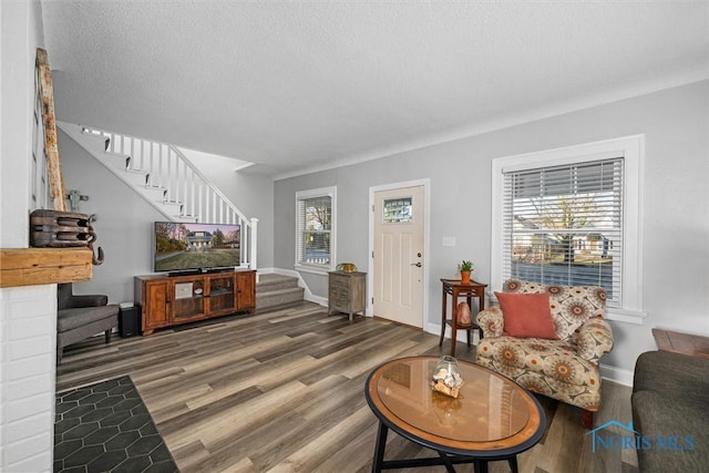 living room with stairway, baseboards, a textured ceiling, and wood finished floors