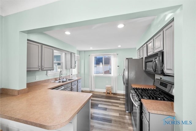 kitchen with gas stove, gray cabinets, black microwave, and a sink