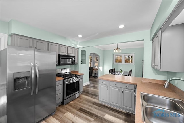 kitchen with a sink, arched walkways, appliances with stainless steel finishes, and gray cabinets