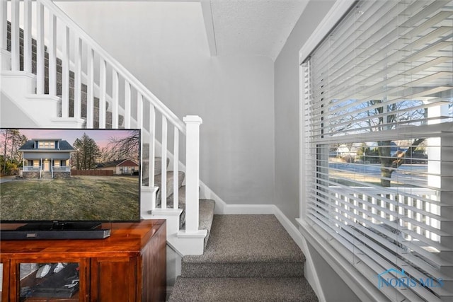 stairs with carpet flooring, a textured ceiling, and baseboards