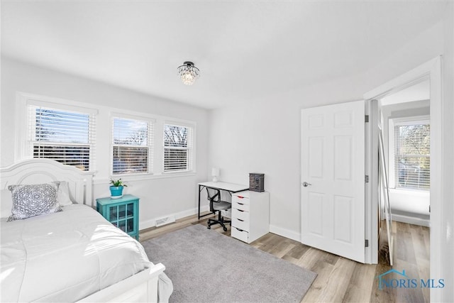 bedroom with visible vents, baseboards, and wood finished floors