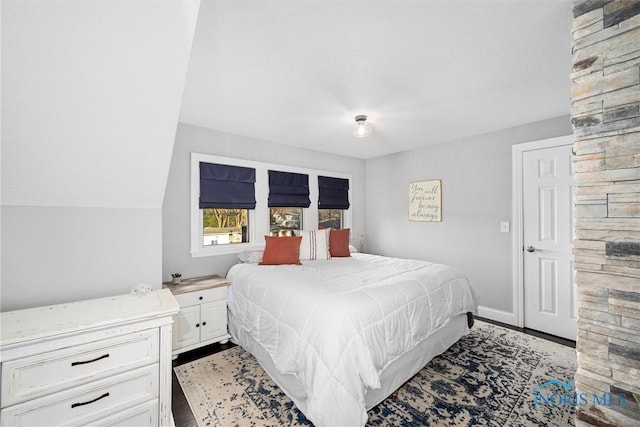 bedroom with lofted ceiling, wood finished floors, and baseboards