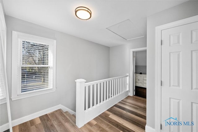 interior space with baseboards, an upstairs landing, attic access, and wood finished floors