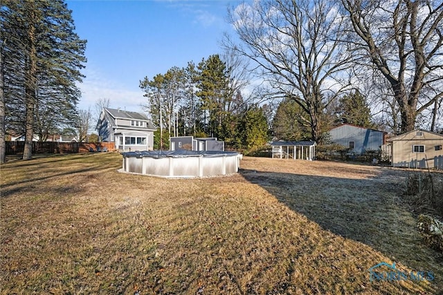 view of yard with a covered pool, an outdoor structure, and fence