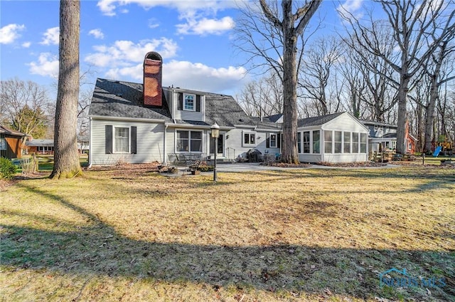 back of property with a lawn, a chimney, and a sunroom