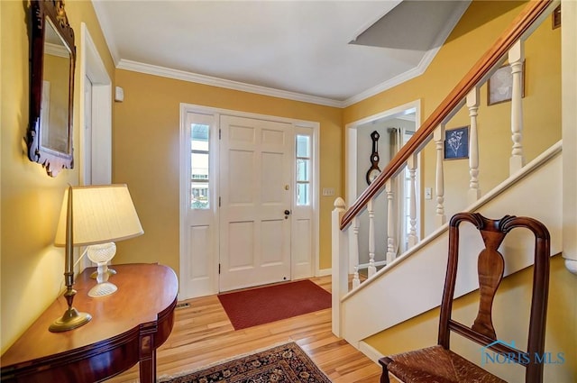 entryway with crown molding, stairway, and wood finished floors