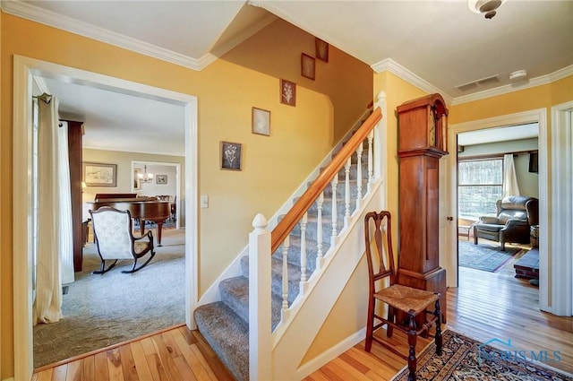 stairway featuring visible vents, baseboards, wood finished floors, and crown molding