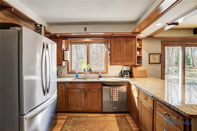 kitchen with a healthy amount of sunlight, a peninsula, stainless steel appliances, and a sink