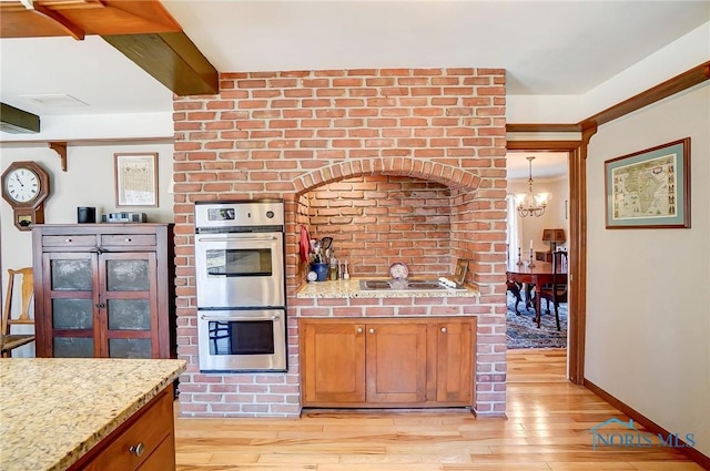 kitchen featuring stainless steel double oven, light wood-type flooring, beam ceiling, and an inviting chandelier