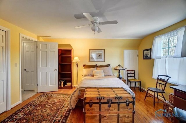 bedroom with a ceiling fan, baseboards, and wood finished floors