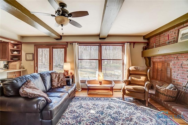 living area with beamed ceiling, wood finished floors, and a ceiling fan