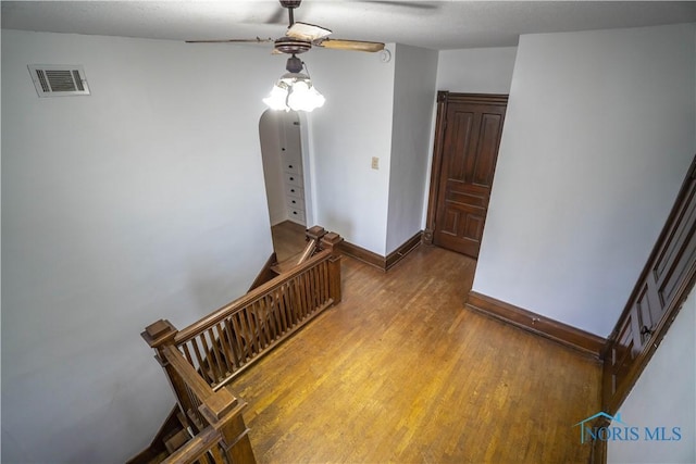 staircase featuring visible vents, baseboards, ceiling fan, and wood finished floors