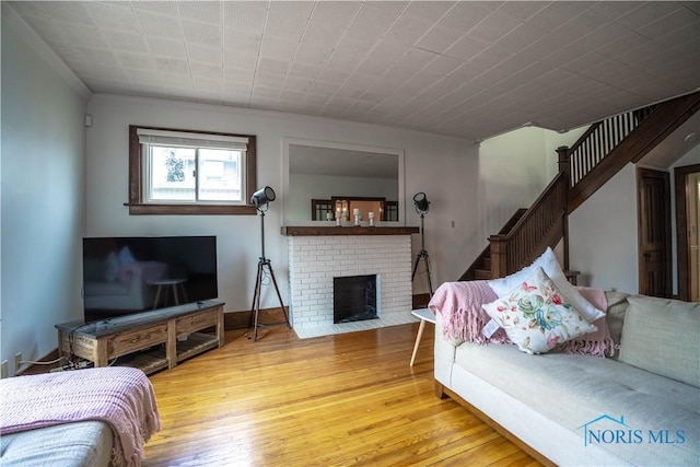 living area with stairway, baseboards, a fireplace, and hardwood / wood-style flooring