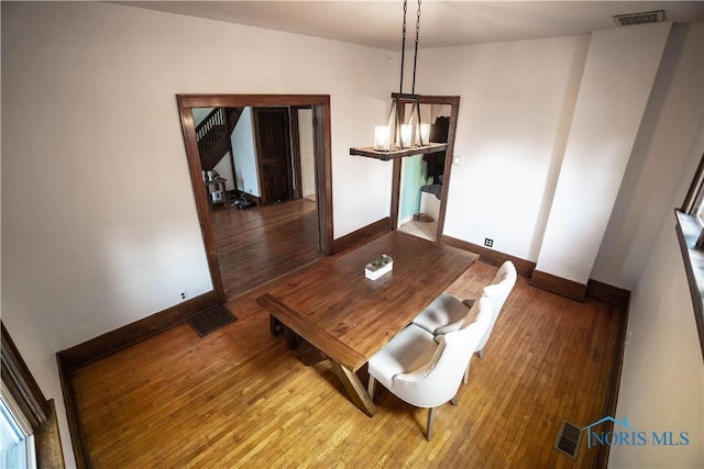 unfurnished dining area with wood finished floors, visible vents, and baseboards