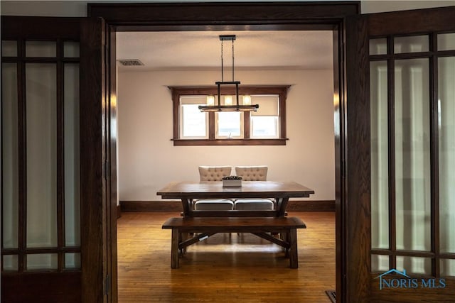 dining space featuring visible vents, baseboards, and wood finished floors